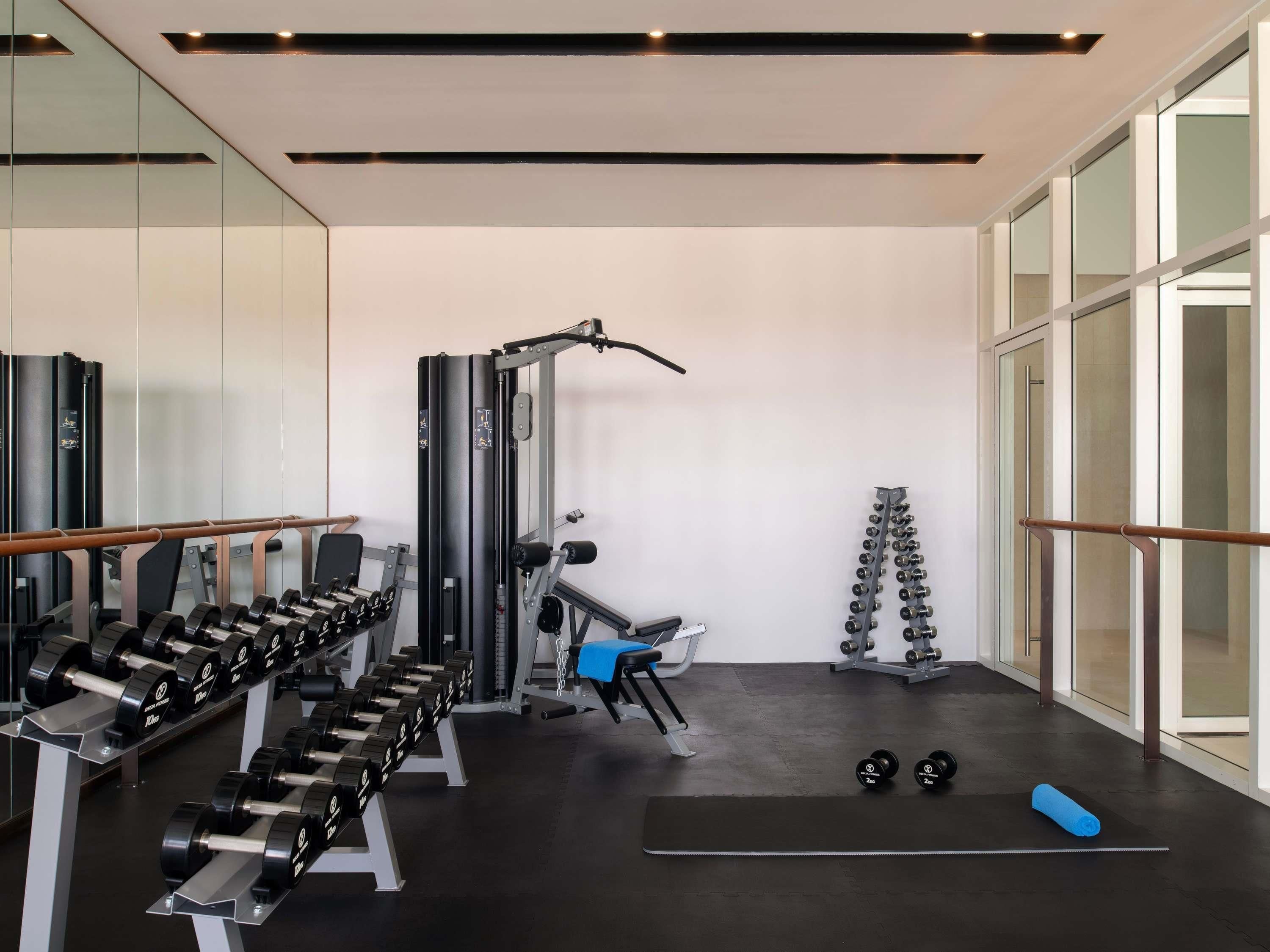 Un gimnasio con equipo de levantamiento de pesas, una banca y una colchoneta.