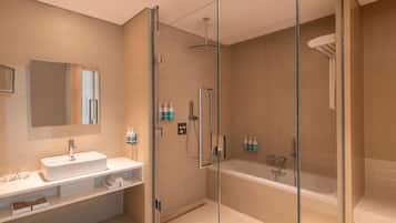 A modern bathroom with a glass-enclosed shower, a large bathtub, and a vanity with a mirror.