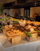 A buffet spread with various breads, pastries, and fruits.