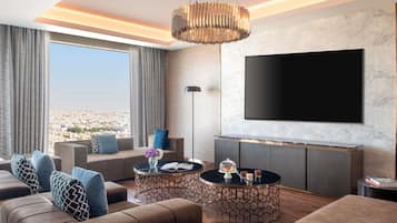 A modern living room with a large TV, comfortable seating, and a city view.