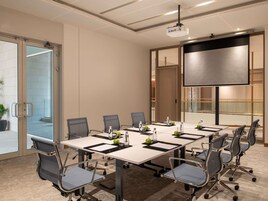 A conference room with a large table, chairs, a projector, and a screen.