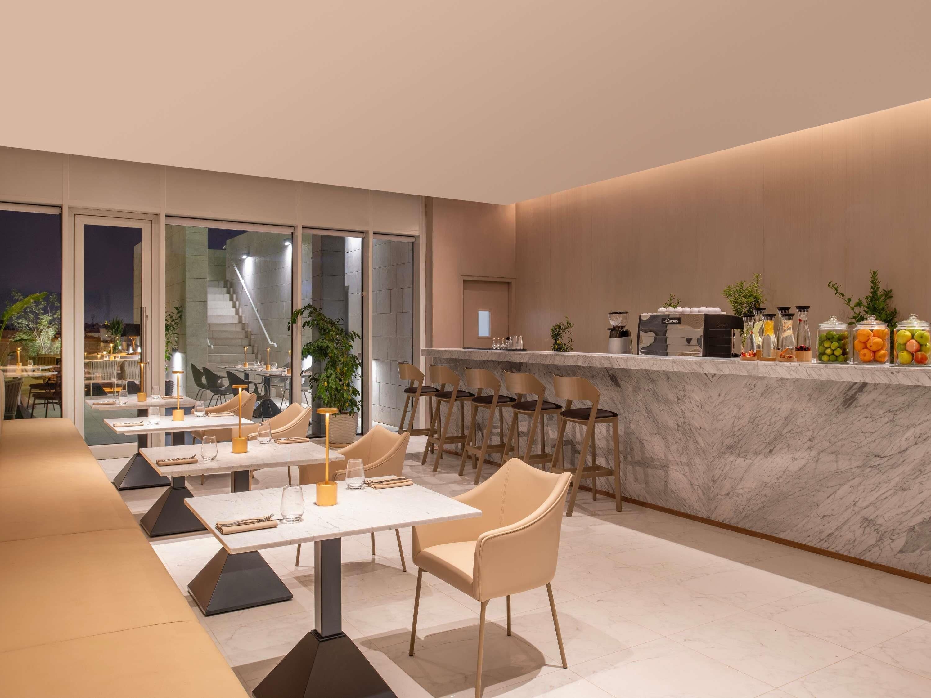 Un restaurant moderne doté d’un bar en marbre, d’un espace salon et offrant une vue sur l’extérieur.