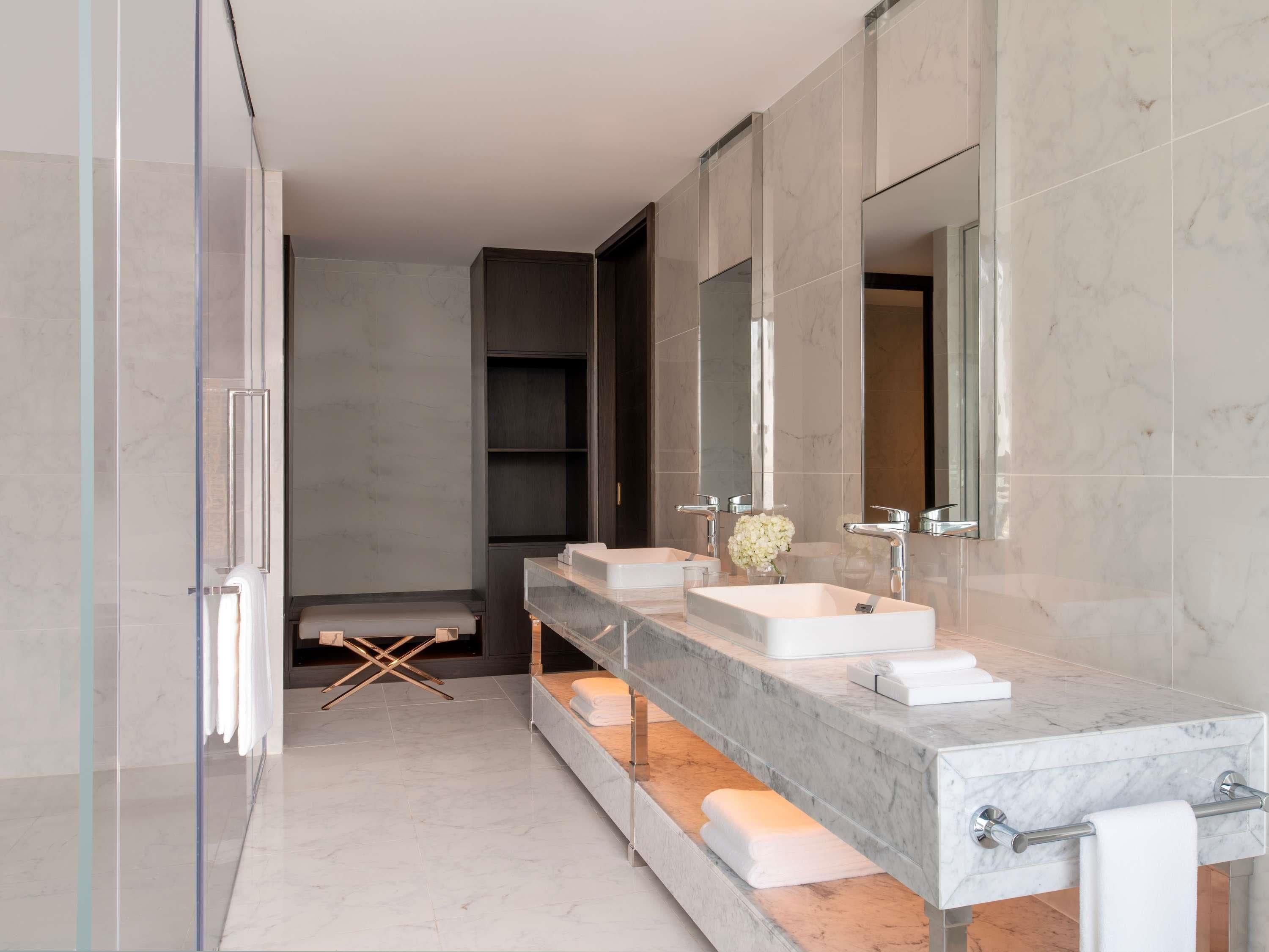 A modern bathroom with two sinks, a large mirror, and a towel rack.