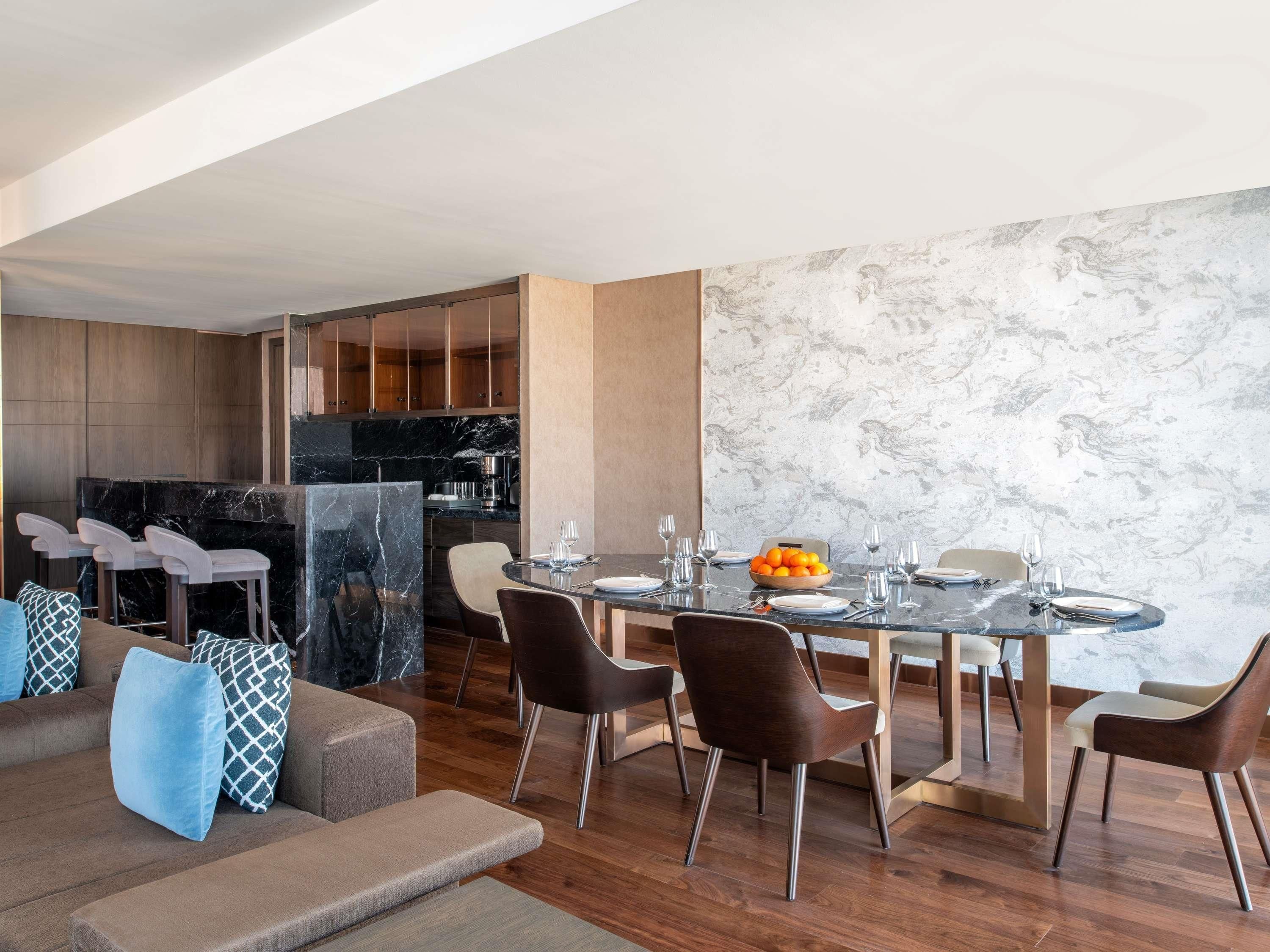 Una sala de estar moderna con comedor, suelo de madera y salpicadero de mármol.