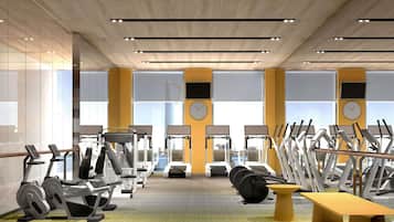 A modern gym with cardio machines, weight stations, and a bench.