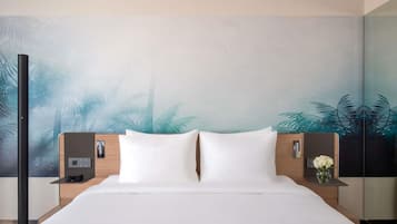 A hotel room with a large bed, two bedside tables, a nightstand, and a wall mural.
