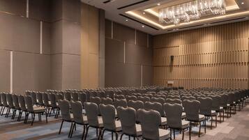 Une salle de conférence avec des rangées de chaises, un pupitre et une moquette à motifs.