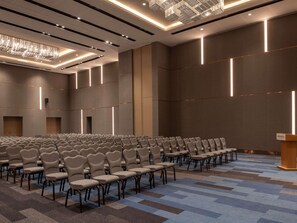 A conference room with rows of chairs, a podium, and modern lighting fixtures. - Novotel Riyadh Sahafa (Riyadh)