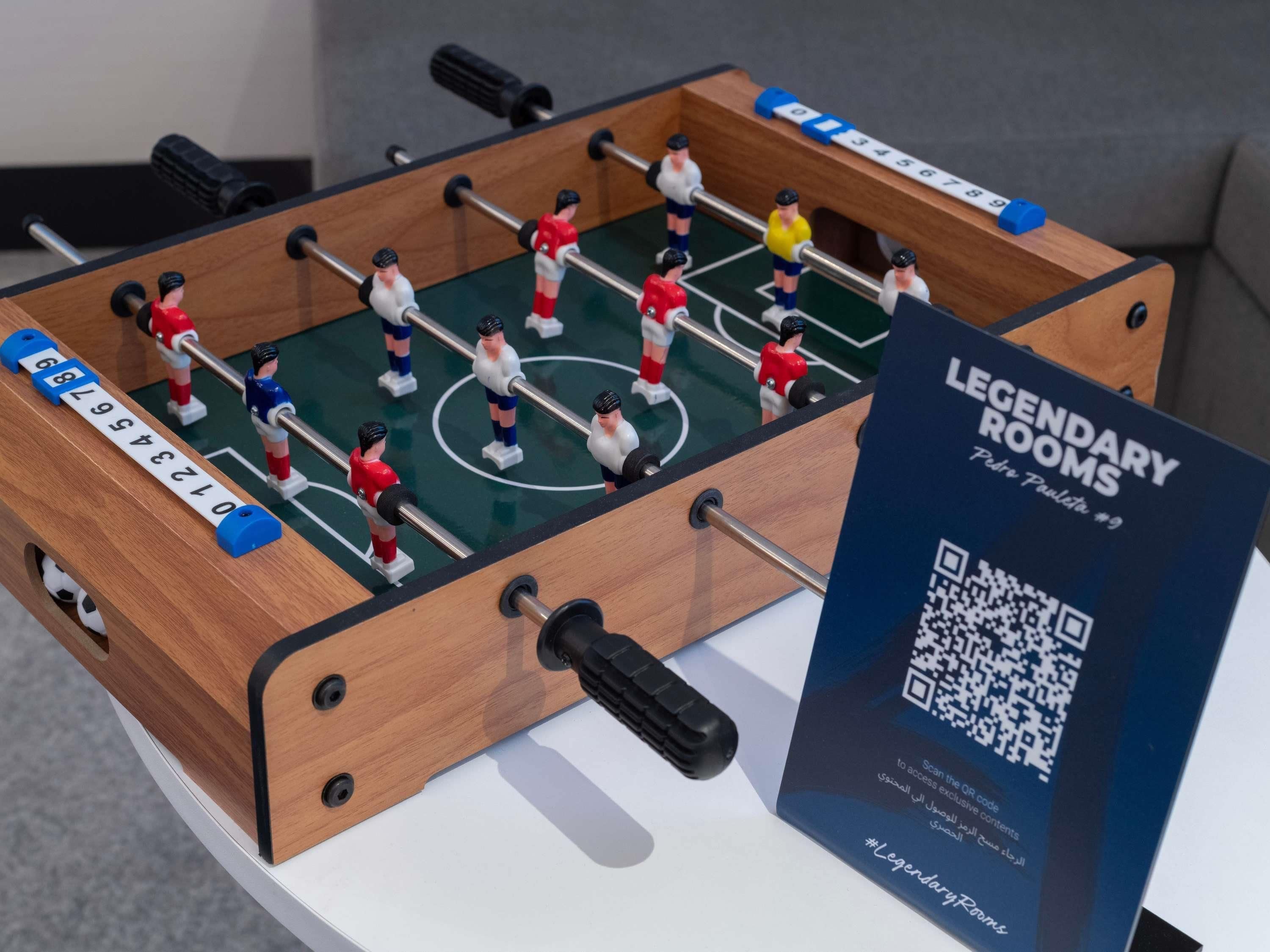 A foosball table with a QR code for 'Legendary Rooms' and a sign indicating it's room #9.