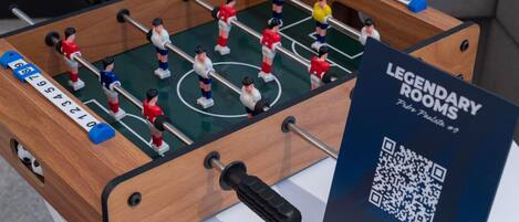 A foosball table with a QR code for 'Legendary Rooms' and a sign indicating it's room #9.