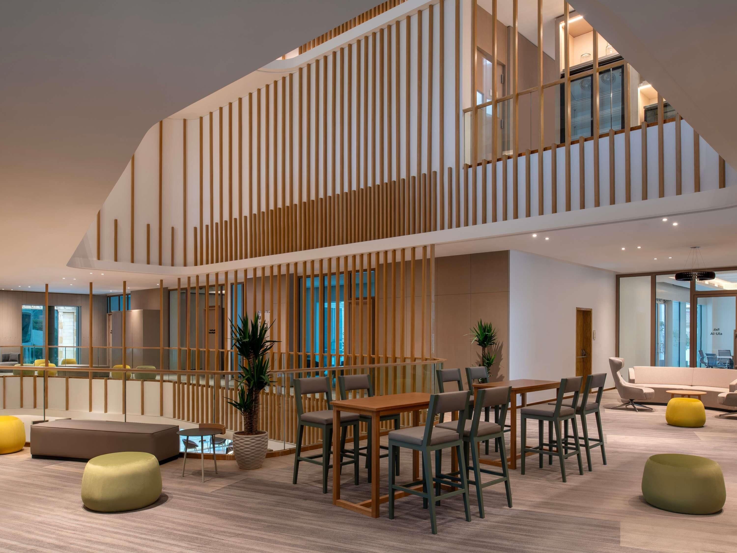 Un intérieur moderne avec un mur à lattes de bois, un espace salon avec des tables et des chaises, et une plante en pot.
