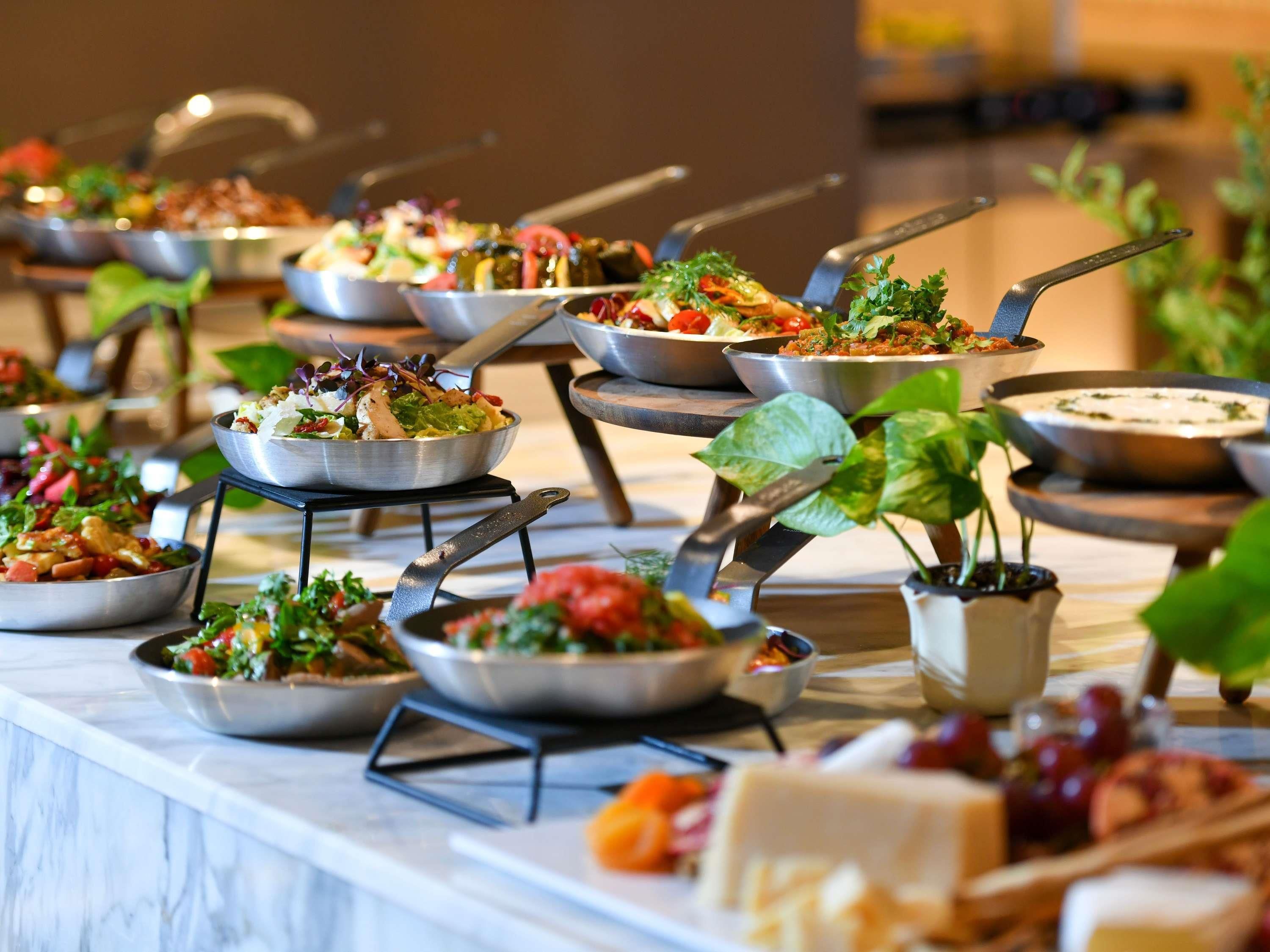A buffet setup with various dishes, including salads and a cheese board, arranged on a marble countertop.