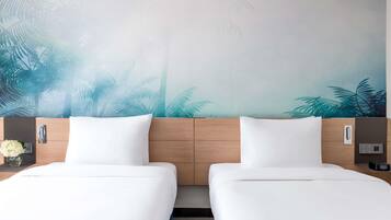 Hotelkamer met twee bedden, een houten hoofdbord, een muurschildering van palmbomen, een nachtkastje met een bloevas en een digitale klok.