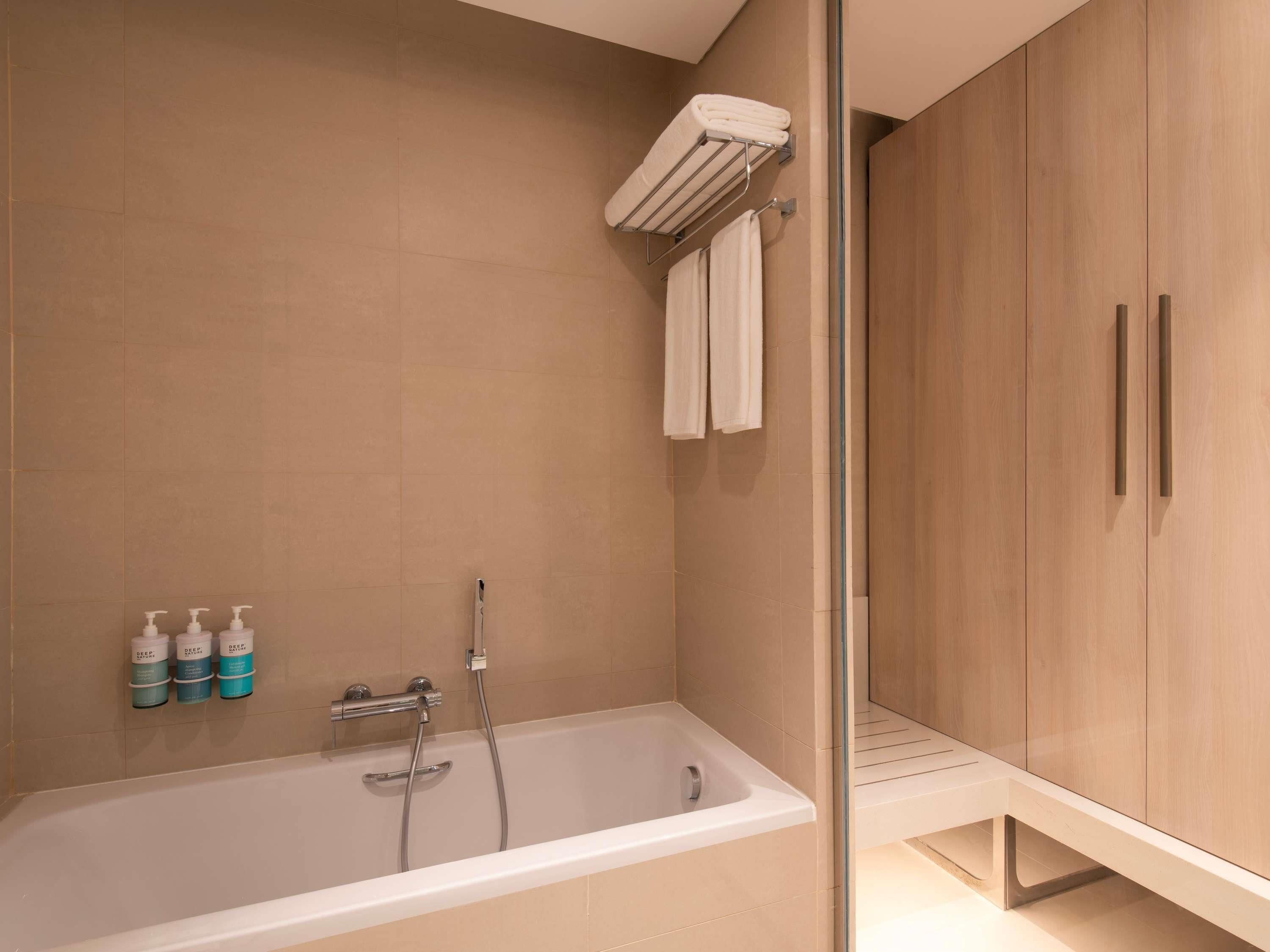 A modern bathroom with a bathtub, a shower, and a vanity with a towel rack.