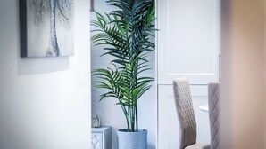 Une pièce moderne avec une grande plante en pot, un meuble blanc et un fauteuil à capitons.