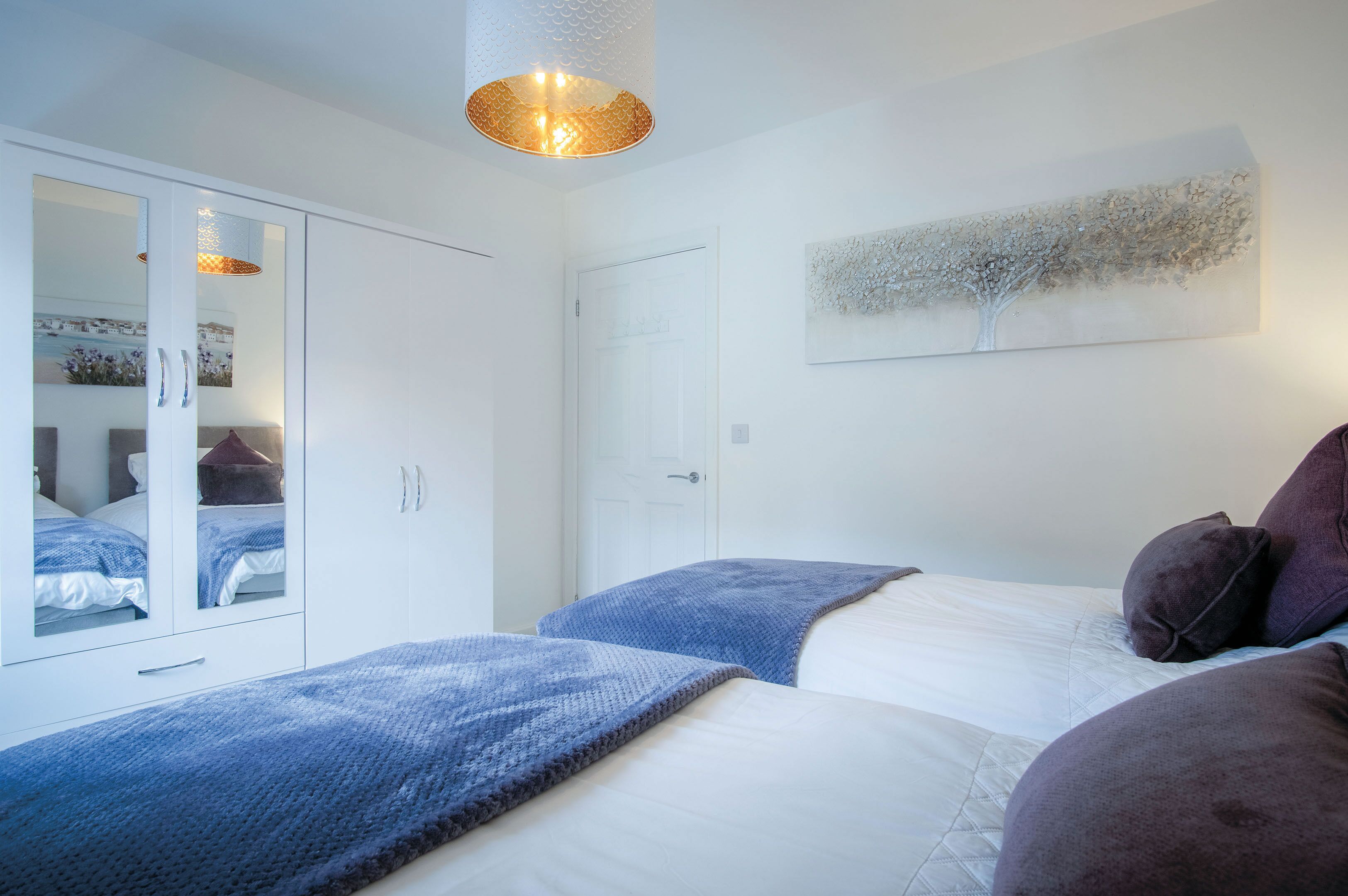 A bedroom with a bed, a wardrobe, and a ceiling light fixture.
