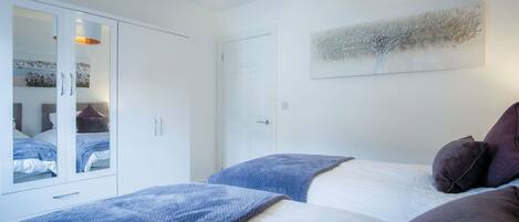 A bedroom with a bed, a wardrobe, and a ceiling light fixture.