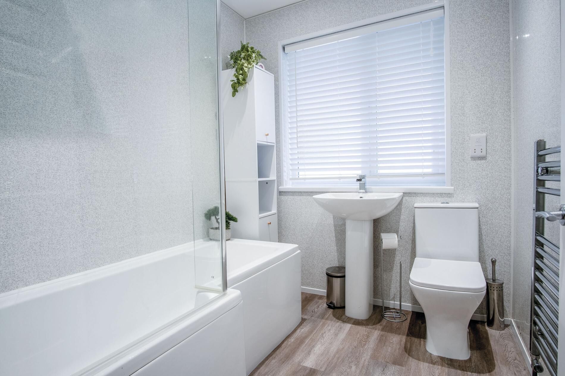 Un baño moderno con bañera, lavamanos, inodoro y una ventana con persianas.