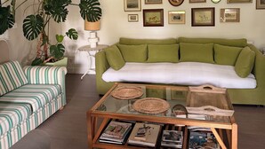 Una sala de estar con un sofá verde, un sillón a rayas y una mesa de centro con revistas.