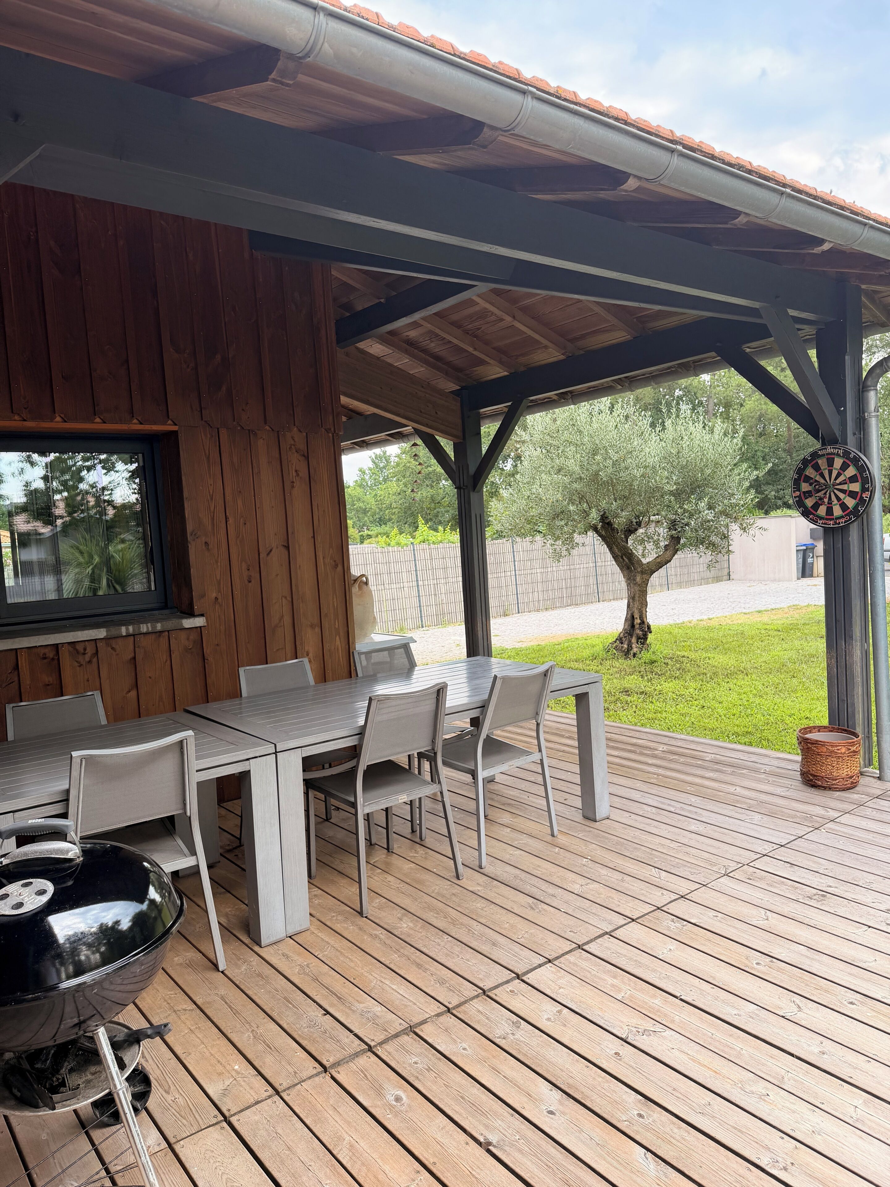 Una terrazza esterna con tavolo, sedie, barbecue e un bersaglio da freccette.