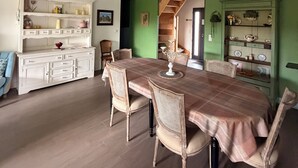 Comedor con una mesa larga, sillas y un aparador blanco con estantes.