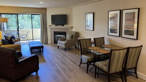 Un salón espacioso con chimenea, televisor y comedor con sillas y mesa.