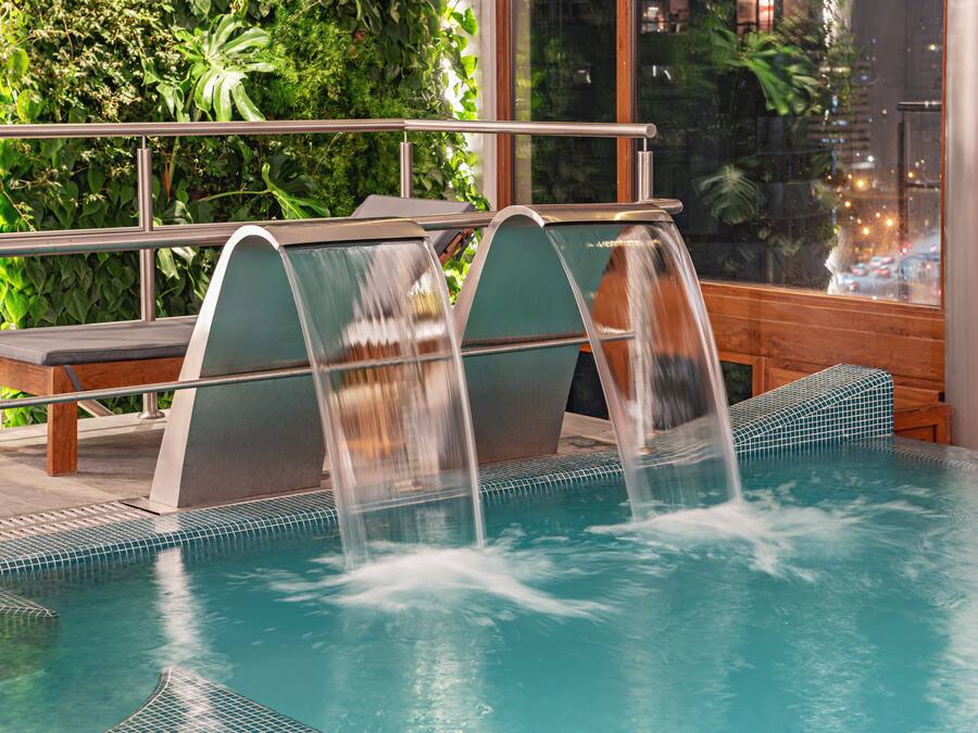 A pool with three water features and a bench.
