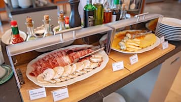 A buffet with various food items including sliced meats and cheeses, labeled with names like "JAMÓN CRUDO" and "AZUL Blue".