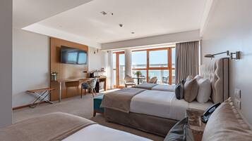 A modern hotel room with two beds, a desk, a TV, and a balcony with a view.