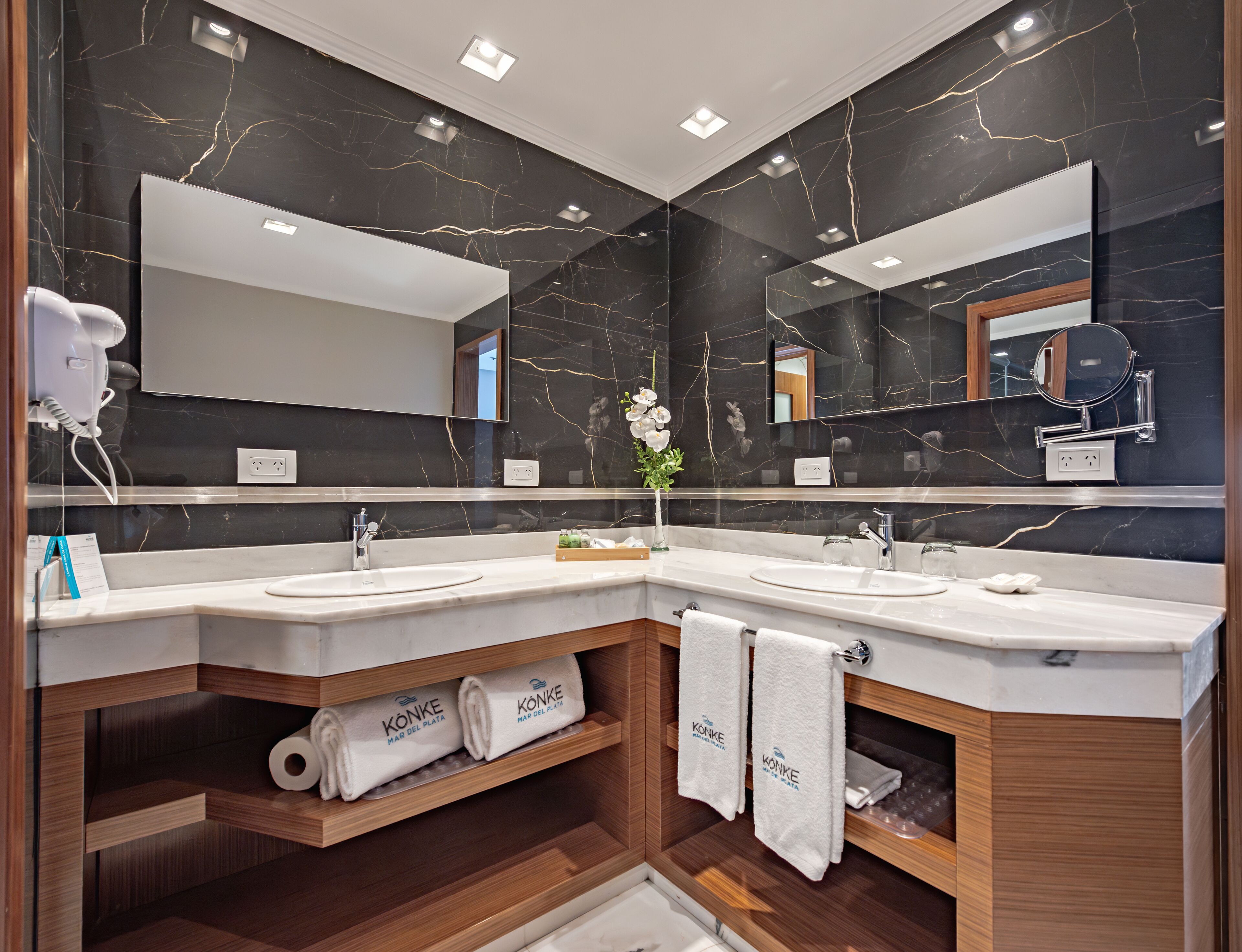 A modern bathroom with two sinks, a large mirror, and a hairdryer.