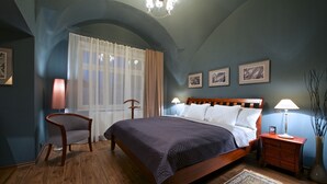 Un dormitorio con una cama, una silla, una mesita de noche y una lámpara.