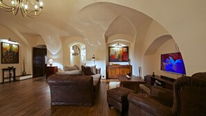 Amplia sala de estar con un sofá, un reposapiés y un televisor.