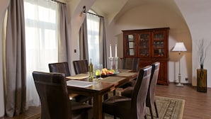 Comedor con mesa de madera, sillas de cuero, una bandeja de frutas, velas y un aparador con puertas de cristal.