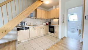 A modern kitchen with wooden cabinets, a dishwasher, a microwave, and a stove. - Ebbe und Flut, Hannoversche Straße 17 OG, 27476 Cuxhaven- Sahlenburg (Cuxhaven- Sahlenburg)