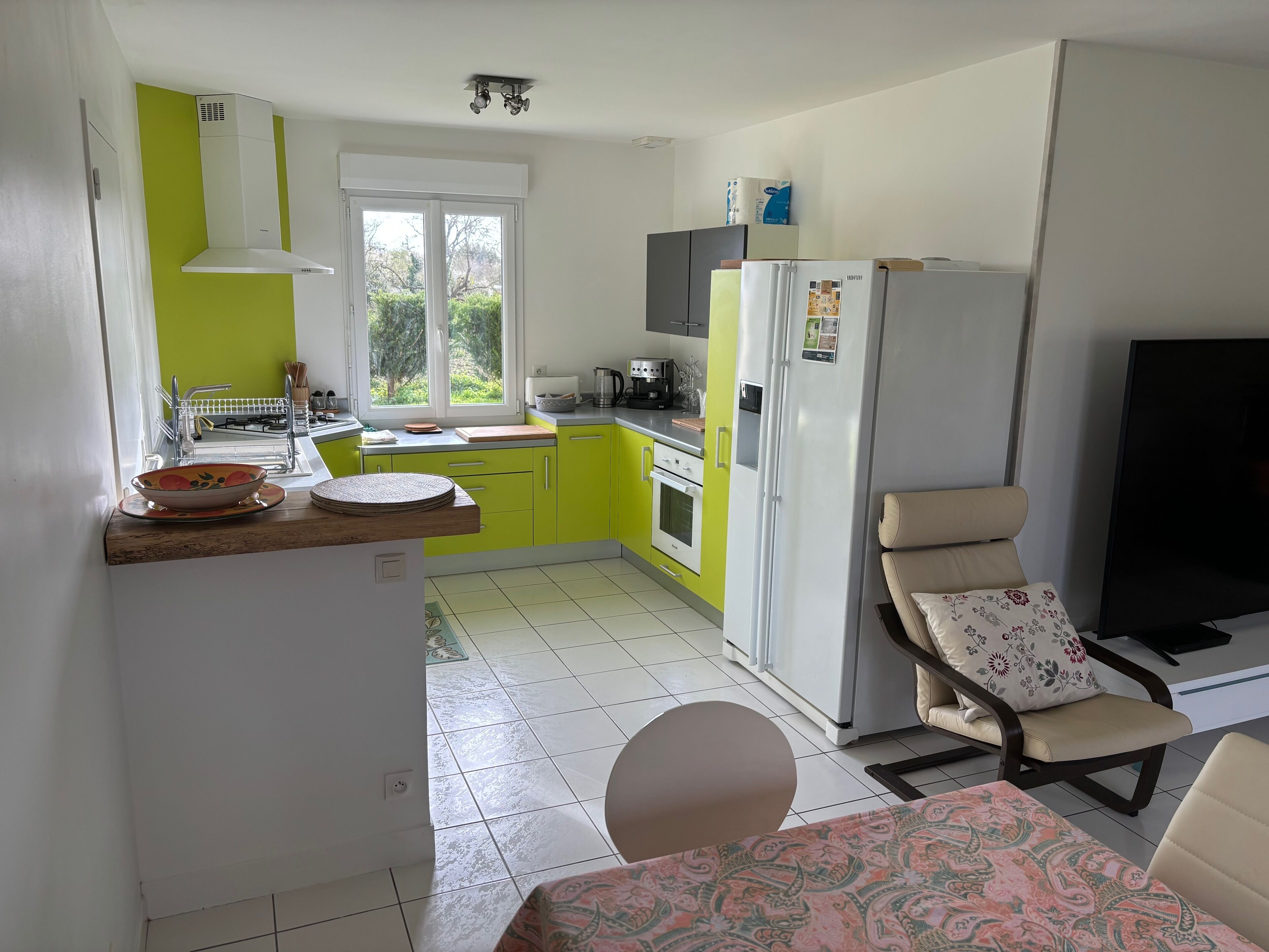 Cocina compacta con ventana, comedor con mesa y sillas, y un televisor.
