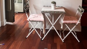 Un área de comedor con una mesa y sillas, una obra enmarcada encima y una puerta que da a otra habitación.