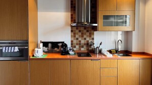 Una cocina moderna con armarios de madera, una campana de acero inoxidable, microondas, cafetera y un fregadero.