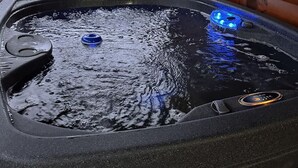 Uma banheira de hidromassagem com deck de madeira e vista para árvores.
