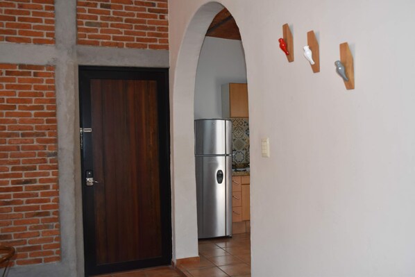 A kitchen with a refrigerator, a wooden door, and a tiled backsplash.