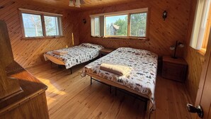 Eine Hütte mit zwei Betten, einem Deckenventilator und großen Fenstern.