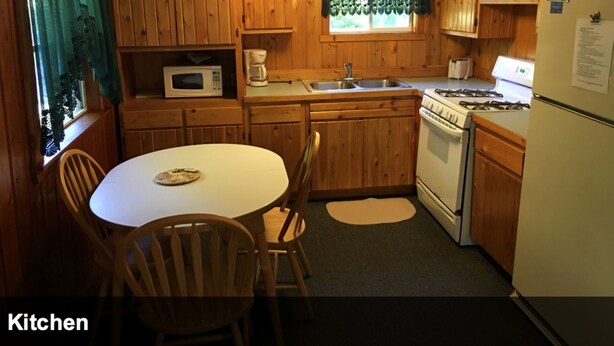 Une cuisine de taille réduite, dotée de meubles en bois, d ’un four à micro-ondes, d’une cuisinière et d’un réfrigérateur.