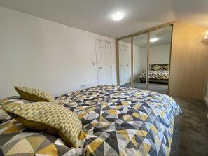 Relax in this serene bedroom with a large bed and stylish wardrobe.