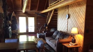 Ein gemütliches Blockhaus-Interieur mit einer Holztreppe, einer Couch, einem Tisch und einer Lampe.