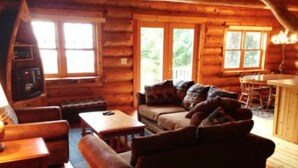 A log cabin interior with a sofa, coffee table, and a television.