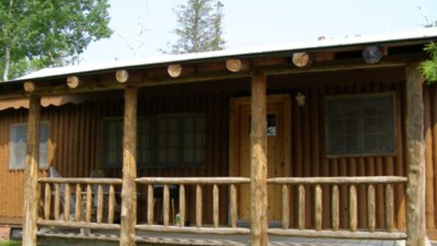 Une cabane en bois avec une véranda, une fenêtre et une porte.