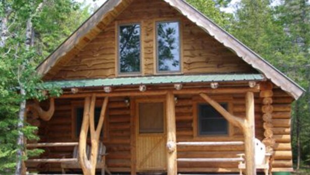 A log cabin with a front porch, two windows, and a door. - Papins Resort Woods Cabin (Drummond)