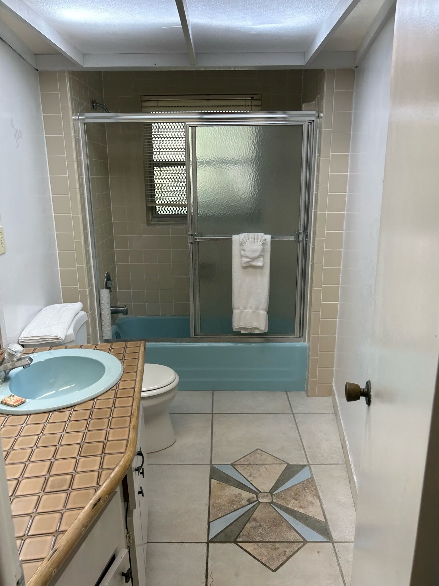 Une salle de bain avec une douche, des toilettes, un lavabo et un carrelage décoratif.
