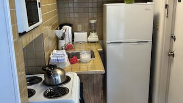 Cozinha compacta com fogão, micro-ondas, torradeira e geladeira.