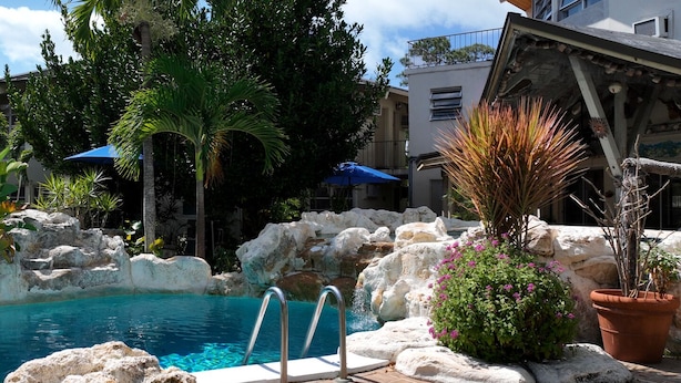 A pool area with a clear blue pool, stone walls, and tropical plants. - Freeport Resort & Club (Freeport)