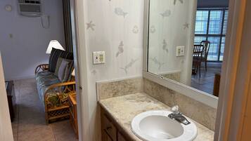 A bathroom with a white sink, a mirror, and a shower area.